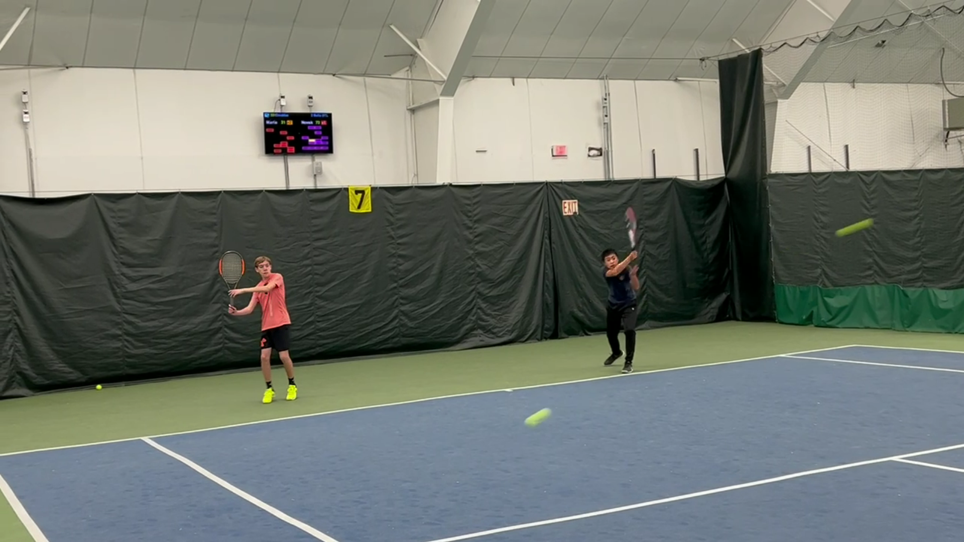 Junior tennis players compete in automated groundstroke drill on smart court