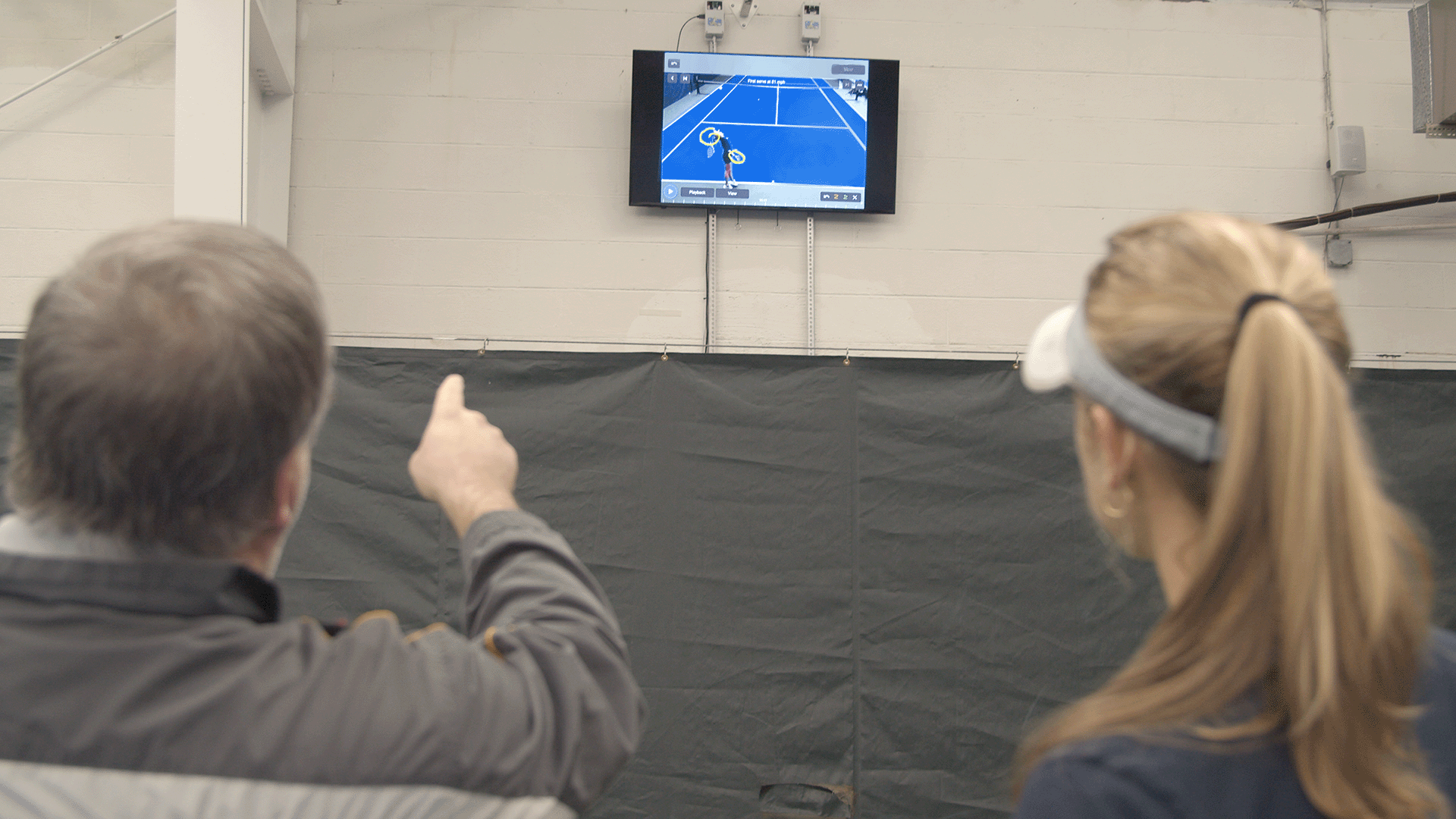 Tennis coach and player using on-court video tools during a lesson