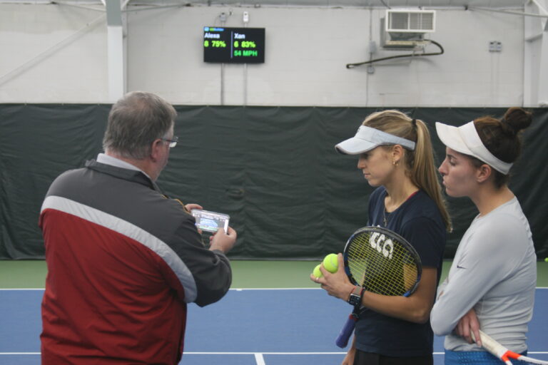 Coach discusses video and analytics for 2 players during an automated tennis drill